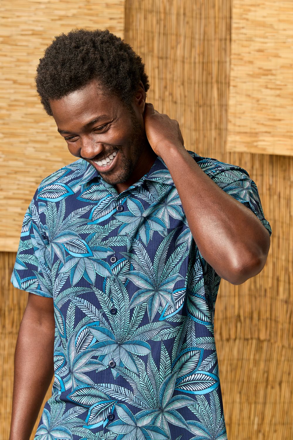 Man wearing a Tommy Bahama blue tropical pattern shirt against a wooden background