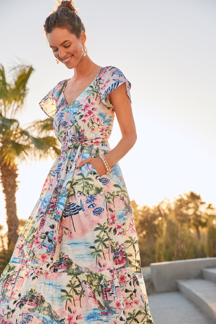 Woman wearing a colorful floral dress with palm trees in the background